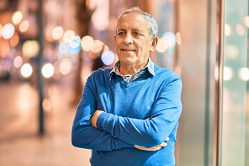 Wall Mural - senior grey-haired man with arms crossed smiling happy standing at the city.