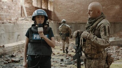 Sticker - POV Female war journalist correspondent wearing bulletproof vest and helmet reporting live near destroyed building, conducting interview with military representative