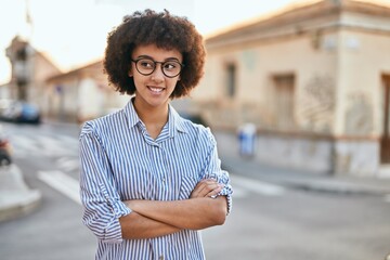 Young hispanic businesswoman with arms crossed smiling happy at the city.