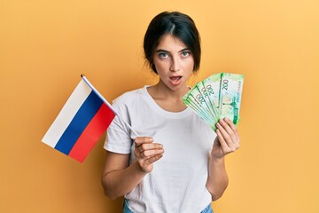 Canvas Print - Young caucasian woman holding pills afraid and shocked with surprise and amazed expression, fear and excited face.