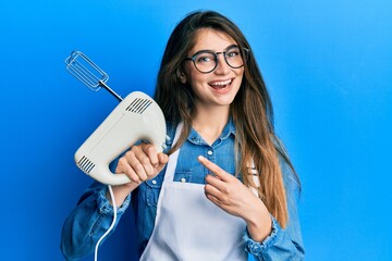 Poster - Young caucasian woman holding pastry blender electric mixer smiling happy pointing with hand and finger