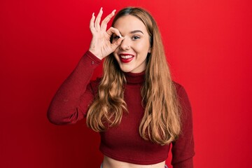 Canvas Print - Young blonde woman wearing turtleneck sweater doing ok gesture with hand smiling, eye looking through fingers with happy face.