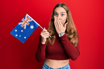 Poster - Young blonde woman holding australian flag covering mouth with hand, shocked and afraid for mistake. surprised expression