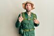 © Krakenimages.com - Handsome man with beard wearing explorer hat and backpack pointing up looking sad and upset, indicating direction with fingers, unhappy and depressed.