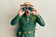 © Krakenimages.com - Handsome man with beard wearing explorer hat looking through binoculars afraid and shocked with surprise and amazed expression, fear and excited face.
