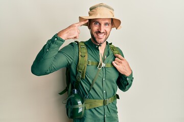 Canvas Print - Handsome man with beard wearing explorer hat and backpack smiling pointing to head with one finger, great idea or thought, good memory