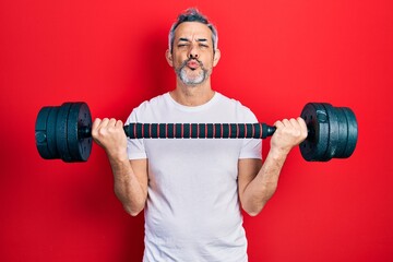 Sticker - Handsome middle age man with grey hair wearing sportswear using dumbbells looking at the camera blowing a kiss being lovely and sexy. love expression.