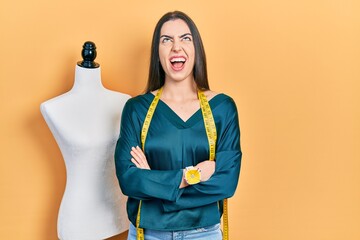 Poster - Beautiful woman with blue eyes standing by manikin with crossed arms angry and mad screaming frustrated and furious, shouting with anger looking up.