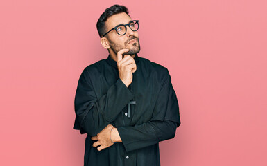 Poster - Young hispanic man wearing priest uniform serious face thinking about question with hand on chin, thoughtful about confusing idea