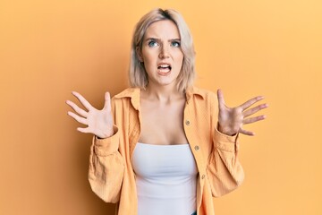 Poster - Young blonde girl wearing casual clothes crazy and mad shouting and yelling with aggressive expression and arms raised. frustration concept.