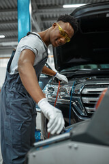 Male worker refills air conditioner, car service