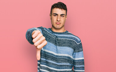 Hispanic young man wearing casual clothes looking unhappy and angry showing rejection and negative with thumbs down gesture. bad expression.