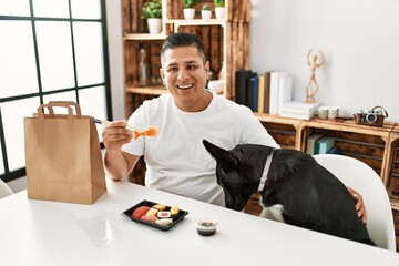 Canvas Print - Young hispanic man eating sushi using chopsticks looking positive and happy standing and smiling with a confident smile showing teeth