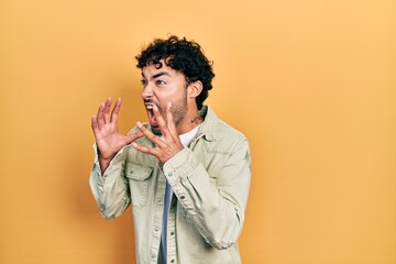 Sticker - Young hispanic man wearing casual clothes shouting and screaming loud to side with hand on mouth. communication concept.