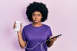 Young african american woman charging smartphone using portable battery depressed and worry for distress, crying angry and afraid. sad expression.