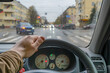 driver hand on the steering wheel inside the car while parking at a traffic light in front of a pedestrian crossing