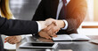 © Iryna - Businessman shaking hands with his colleague above the glass desk in sunny modern office, close-up. Unknown business people at meeting