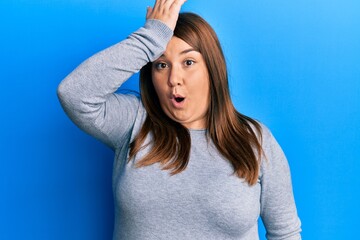 Beautiful brunette plus size woman wearing casual clothes surprised with hand on head for mistake, remember error. forgot, bad memory concept.