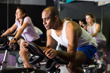 Portrait of sporty man training on stationary bike in gym