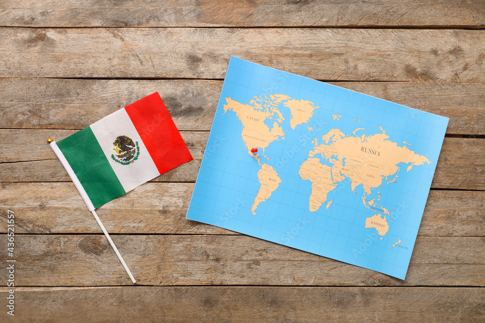 World map with pin and Mexican flag on wooden background