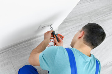 Poster - Young electrician repairing socket in room