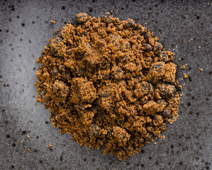 pile of dark muscovado cane sugar closeup on black