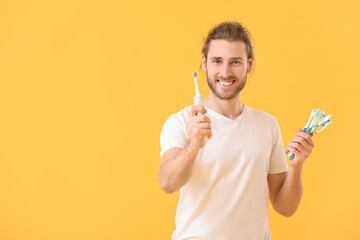 Poster - Young man with tooth brushes on color background