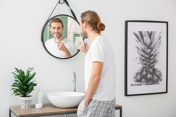 Poster - Young man brushing teeth in bathroom