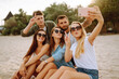 © maxbelchenko - Group of people doing selfie with phone at the beach. Young friends enjoy summer party together. People, lifestyle, travel, nature and vacations concept.