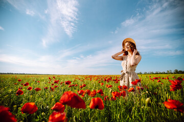 Young woman walking in amazing poppy field. Summertime. Beautiful woman posing in the blooming poppy field. Nature, vacation, relax and lifestyle.