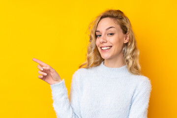 Poster - Young blonde woman isolated on yellow background pointing finger to the side