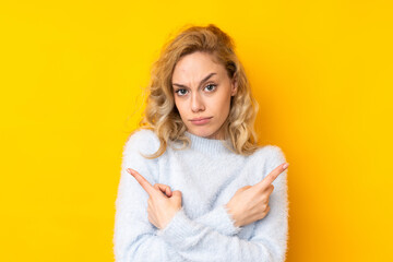 Poster - Young blonde woman isolated on yellow background pointing to the laterals having doubts