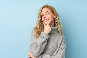 Canvas Print - Young blonde woman wearing a sweater isolated on blue background smiling