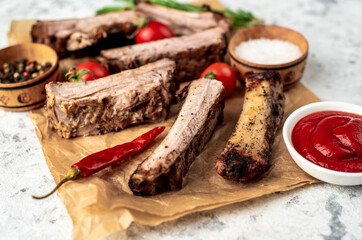 chopped pork ribs on the grill on a light stone background