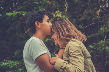 HAPPY YOUNG COUPLE IN LOVE KISSING IN THE FOREST