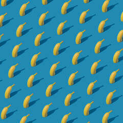 Creative fruit pattern arrangement with halved banana on bright blue background. Minimalistic geometric concept, colorful summer idea.