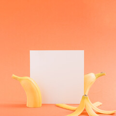 Creative minimalistic copy space idea with a white card on bright pastel red background with fresh bananas. Authentic fruit idea, summer colorful concept.