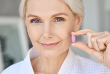 Closeup Portrait Of Happy Middle Aged 50s Woman Holding Pill Taking Dietary Supplements. Portrait Of Smiling Adult Attractive Woman Taking Collagen Vitamins Health In Menopause.