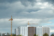 Modern construction of a multi-storey building in cloudy day. Modern high-rise building. Residential area. Cranes build multi-storey buildings. High quality photo