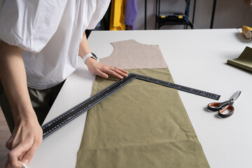 Wall Mural - Tailor couturier measuring fabric. Closeup of professional sewer female use triangle ruler to cut material for sewing. Garment atelier equipment. Creative work process in fashion design studio concept