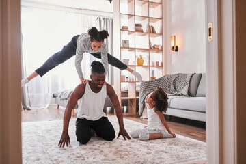 Wall Mural - Father sitting at the floor at home while his little daughters having fun