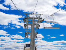 Open Cable Car, Chairlift With Empty Seats On The Background Of A Blue Sky With Clouds, A View From Below Of The Ascent. The Concept Of A Dangerous, Risky Lift.