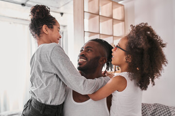 Wall Mural - Two multiracial girls sitting at the hands of their strong single father