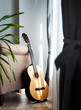 Vertical shot of a classical guitar leaning on a sofa under the sunlight through the windows