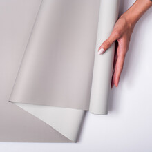 Closeup Of A Woman Holding A Roll Of Gray Wallpaper Against A White Background