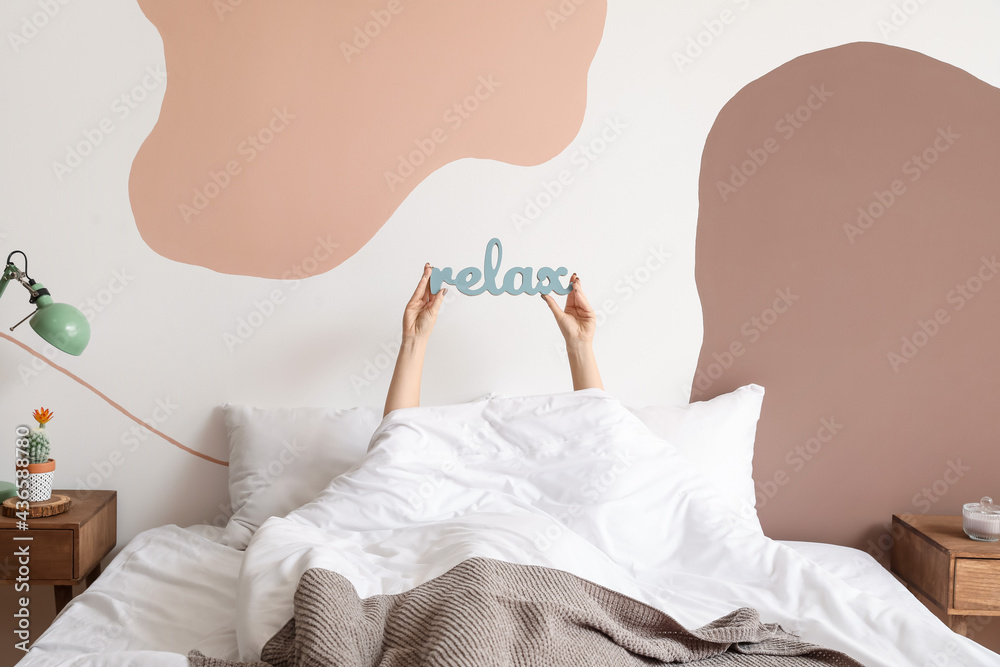 Young woman with word RELAX in bedroom