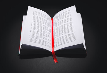 Wall Mural - Open book with bookmark on dark background