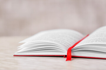 Wall Mural - Open book with bookmark on light background, closeup