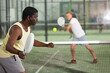 © JackF - Concentrated american man padel player hitting ball with a racket at fitness health club