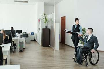 Sticker - Disable businessman in wheelchair passing paper to his secretary in open space office